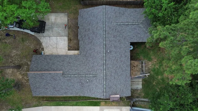 alt="roofing in spring, tx showcasing an above shot of a new asphalt shingle roof replacement with green trees"