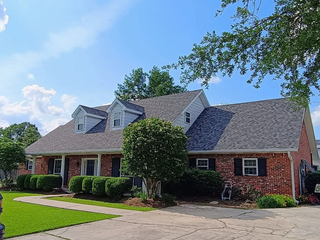 alt="roof repair in spring tx on brick home with blue sky"