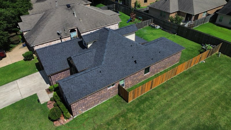 alt="side view of large home with new rood replacement after hail damage in spring"